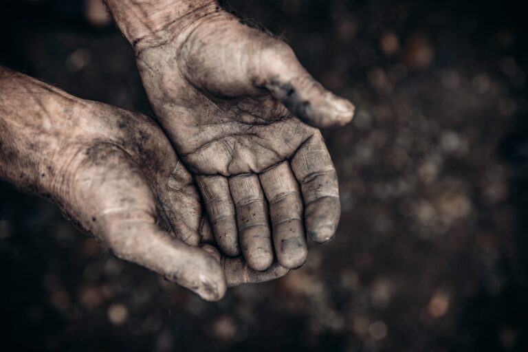 Two palms in mud and calluses are pointing up, hands of refugee and homeless